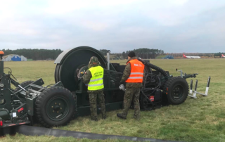 Dwóch techników przy systemie awaryjnego hamowania samolotu BAK-12 na lotnisku w Bydgoszczy